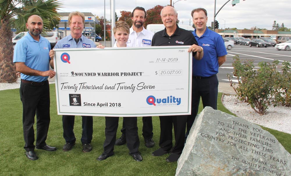 Quality Tune-Up Car Care team holding large check showing donation of $20,027.00 for Wounded Warriors Project | Quality Tune Up Car Care Center